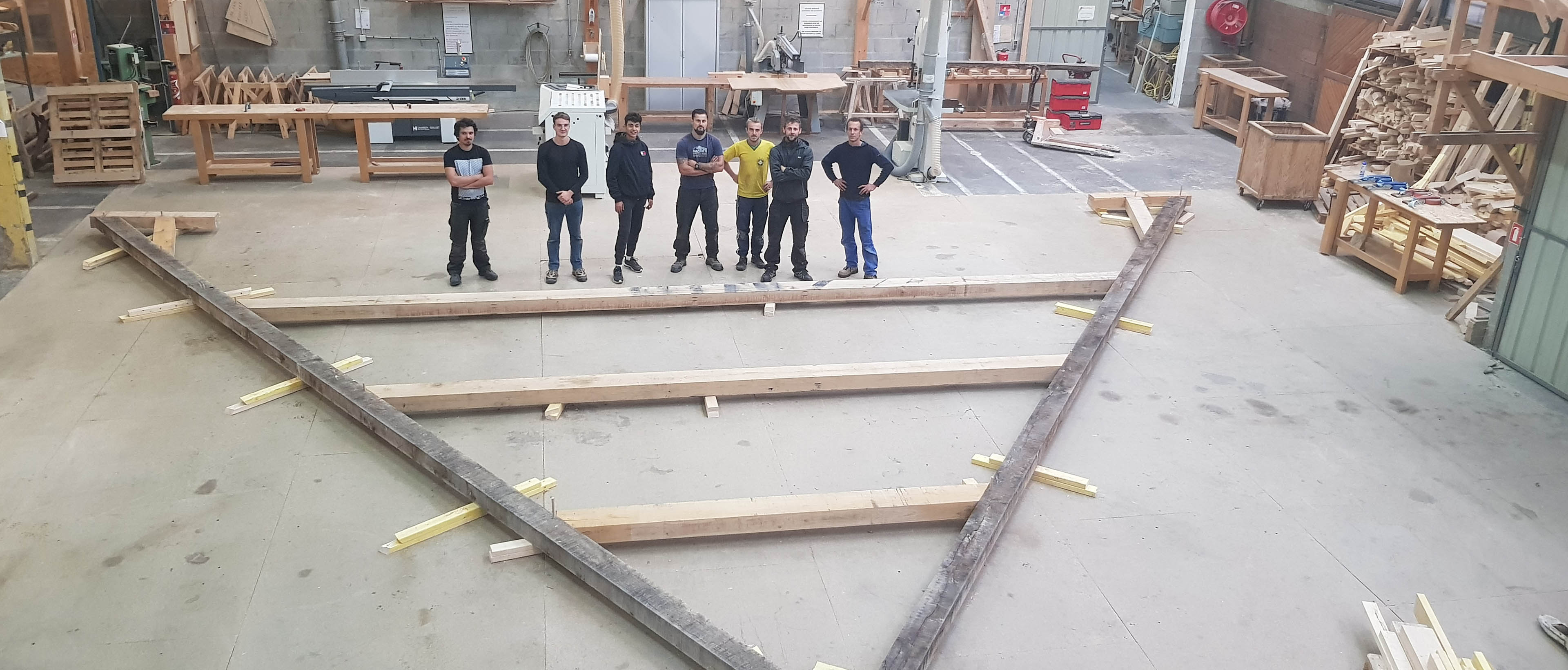 Jeunes apprentis posent devant une partie de la maquette de la charpente de Notre Dame