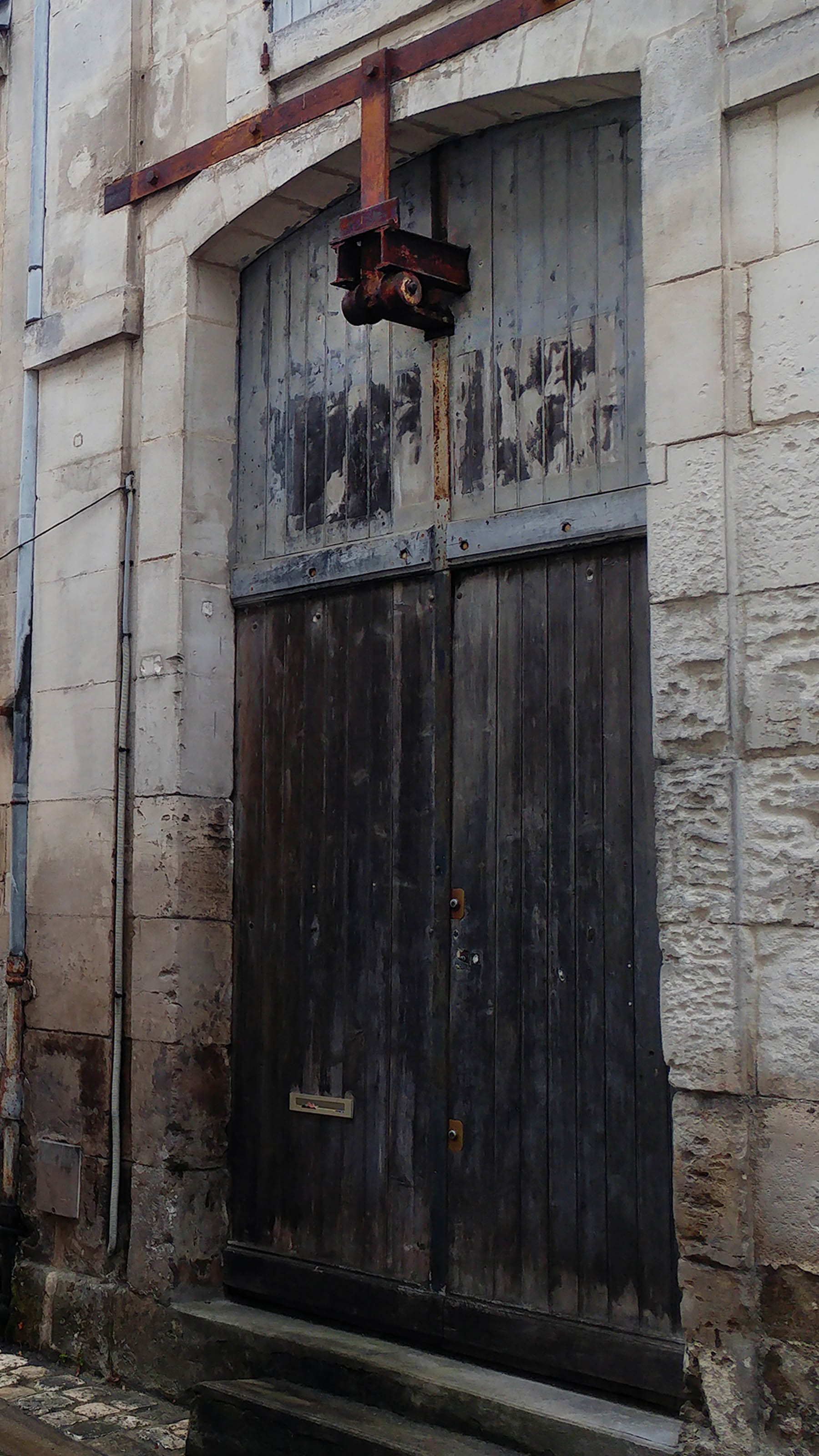 Porte d'entrepôt surmontée d'une poulie dans la rue Saulnier, à Cognac