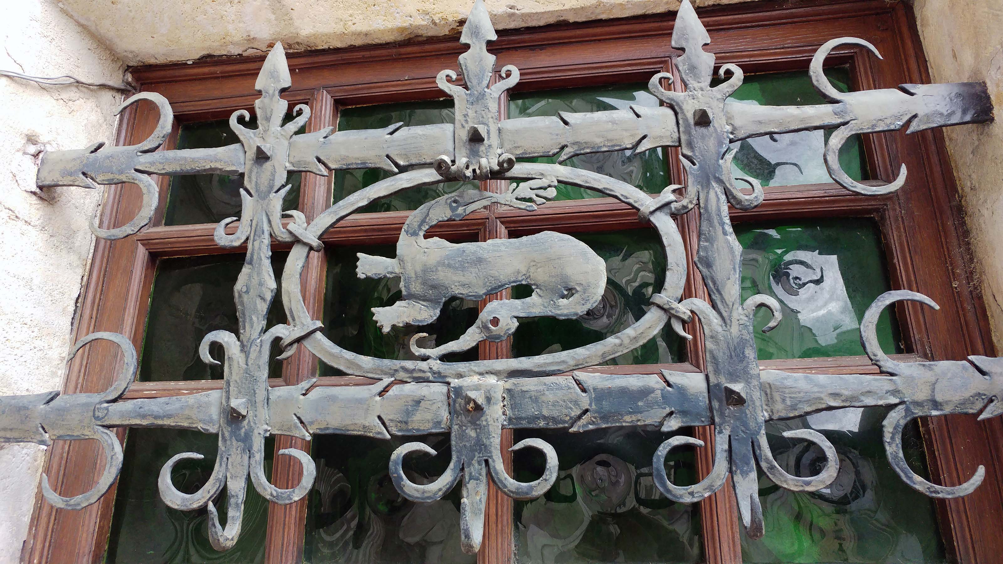 Une grille en fer forgé en forme de salamandre protège une fenêtre donnant sur une rue du vieux Cognac, en Charente