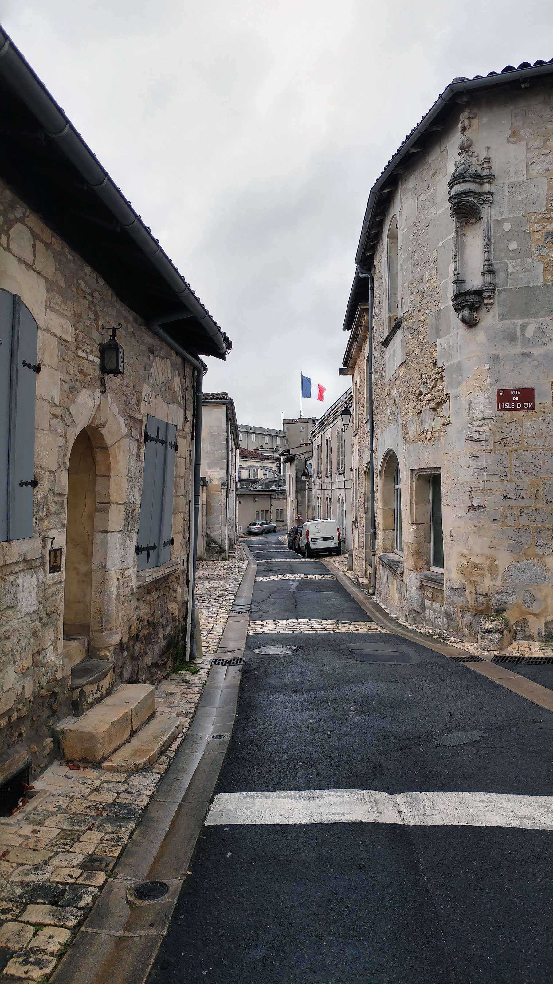 Rue du vieux quartier de Cognac, avec un drapeau tricolore à l'horizon