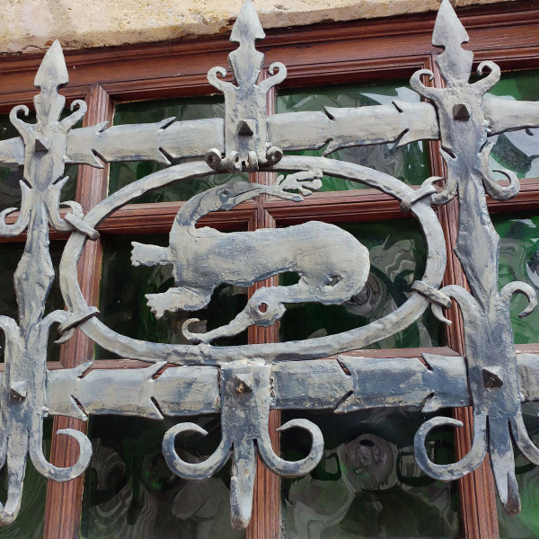 Une grille en fer forgé en forme de salamandre protège une fenêtre donnant sur une rue du vieux Cognac, en Charente