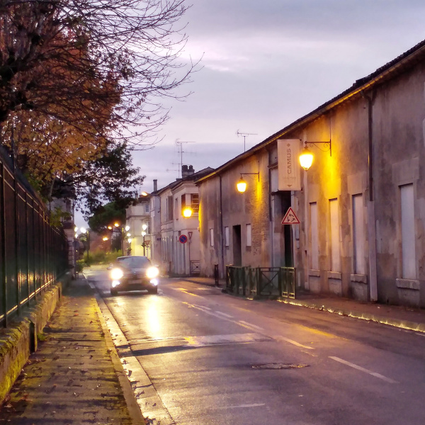 Une rue de Cognac la nuit, éclairée par les phares d'une voiture