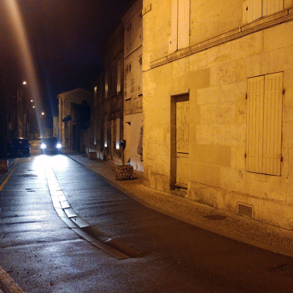 Vieux quartier de Cognac de nuit, éclairé par les phares d'une voiture.