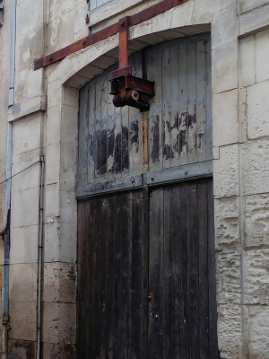 Porte d'entrepôt surmontée d'une poulie dans la rue Saulnier, à Cognac