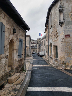Rue du vieux quartier de Cognac, avec un drapeau tricolore à l'horizon